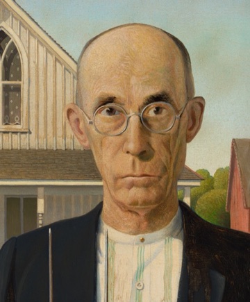 The man looks directly at us through round glasses.