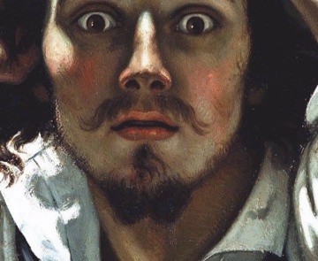 His lips part beneath a dark moustache.